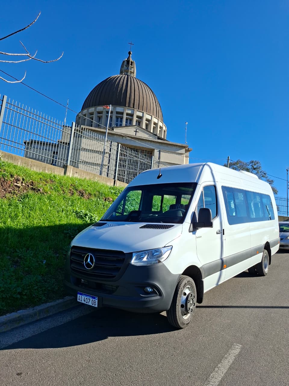 Combi Mercedes-Benz blanca de Hamal Micro Bus estacionada frente a iglesia